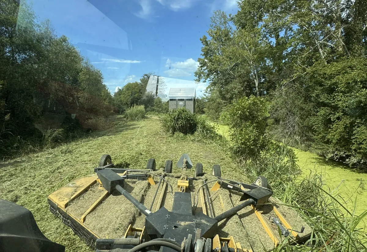 Disc harrow breaking ground for a fall food plot, seen from the tractor cab in Northeast Louisiana